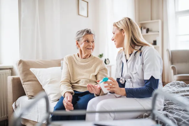 old woman and nurse sitting on bed 